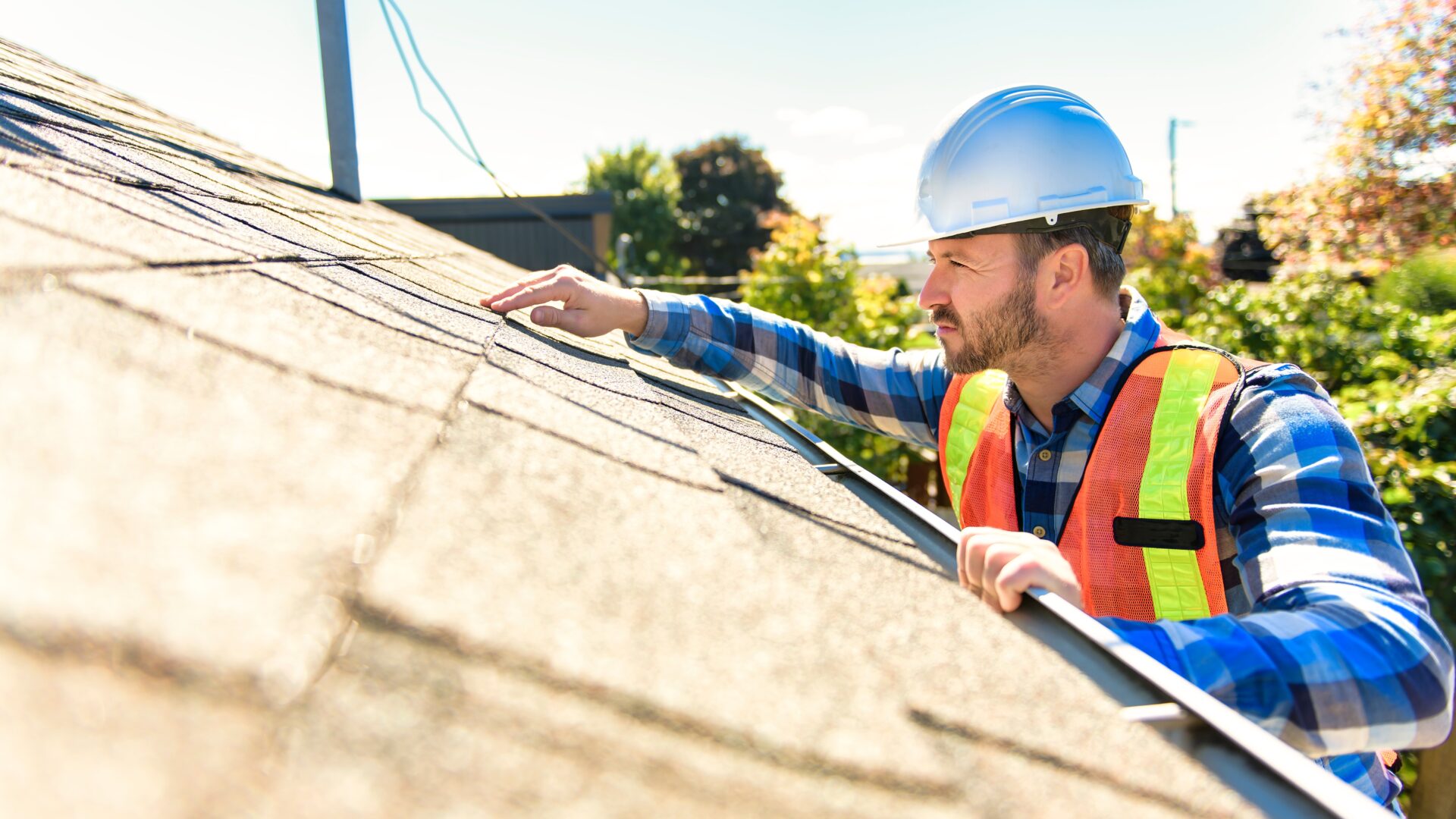 Roofer inspecting a shingle roof during maintenance