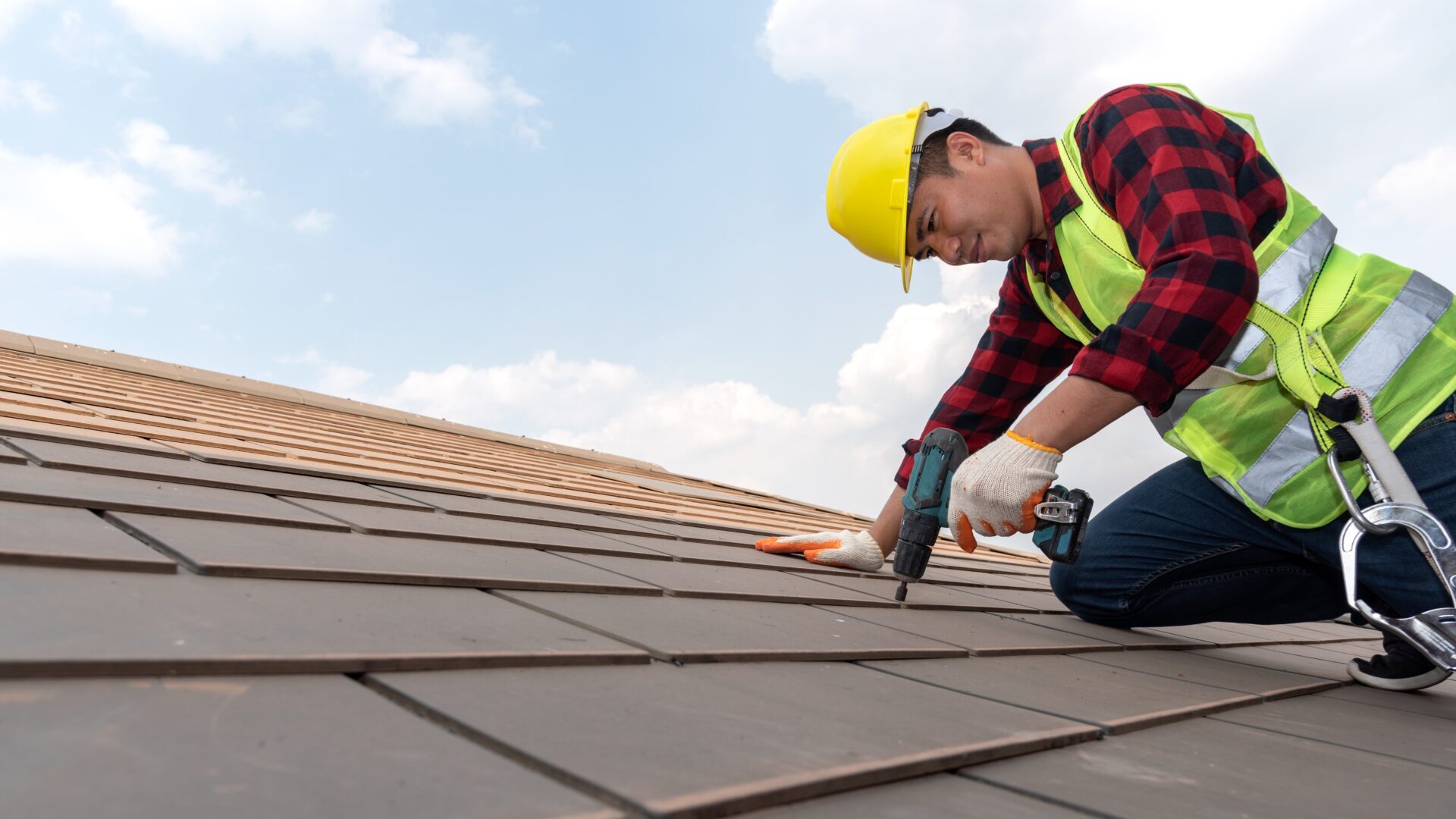 A roofer performs repairs on a tile roof