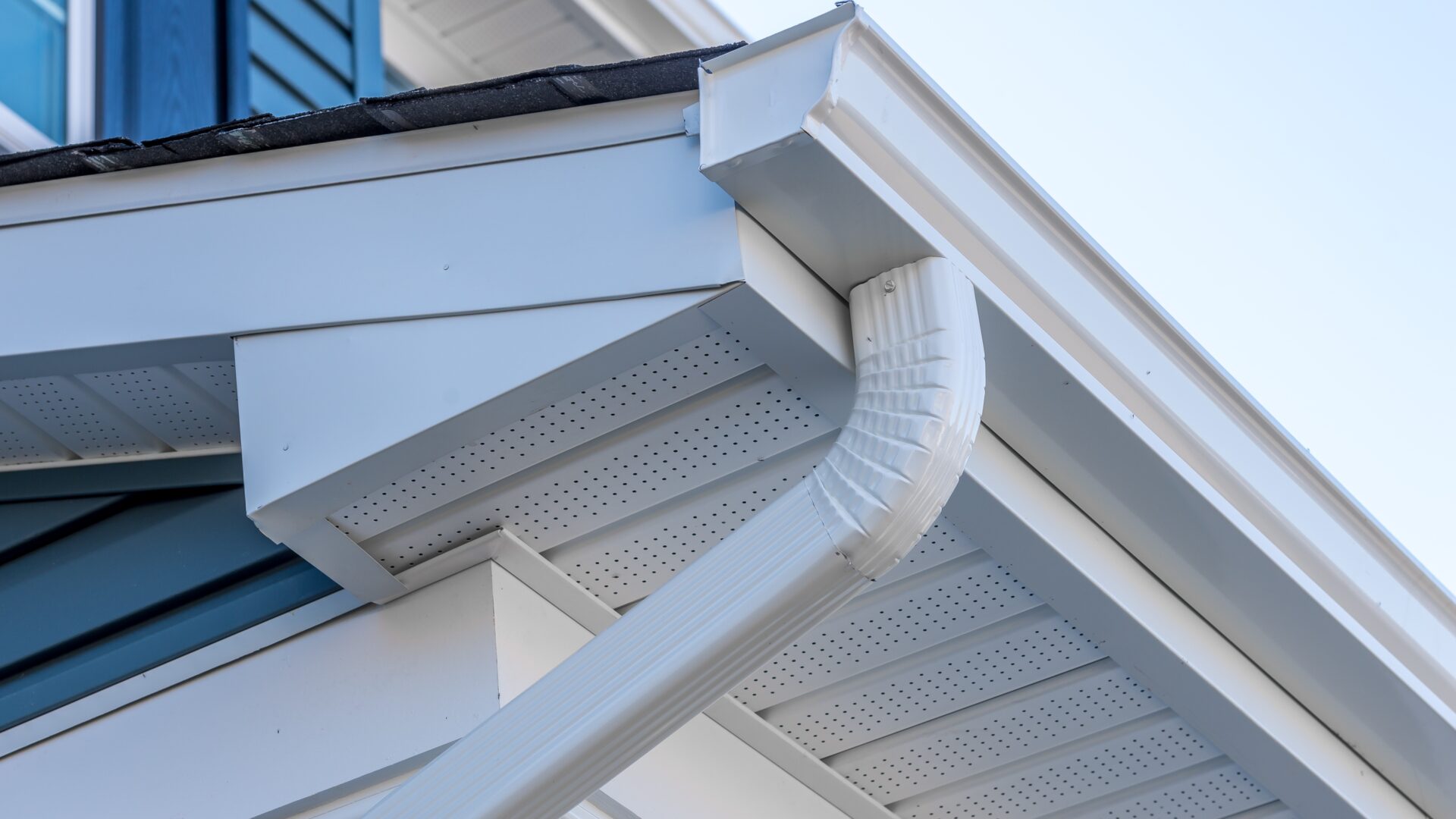 A white seamless gutter with white downspout