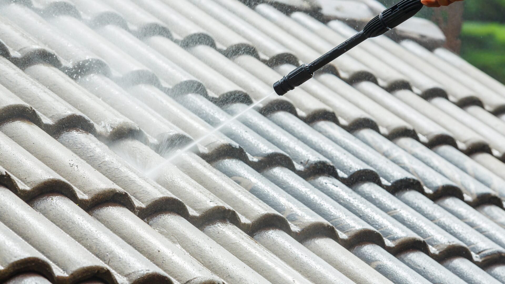 Closeup of tile roofing being sprayed with cleaner